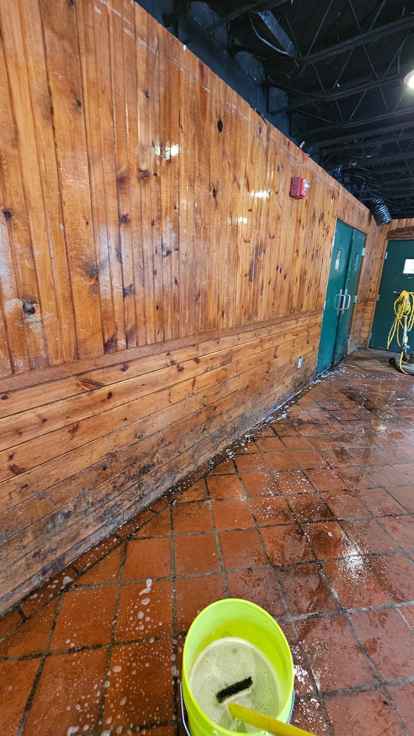 Wood-paneled room with debris and uneven floor appearance before work